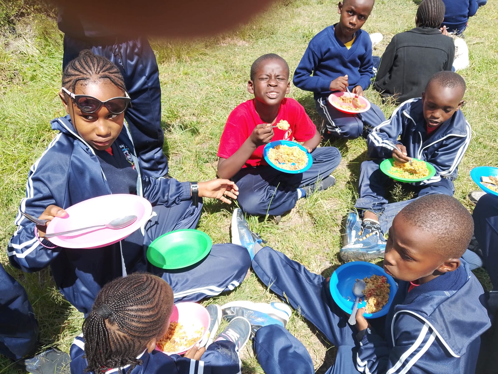 Learners sharing a hot lunch outdoors at Blessed Gilgal School